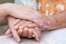 elderly female hands holding the hands of a young woman