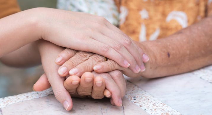 elderly female hands holding the hands of a young woman