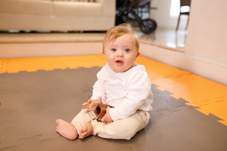 Down syndrome baby sitting down on the living room