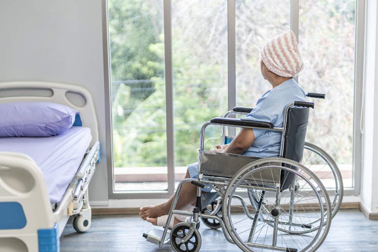 Senior female is cancer patients on wheelchair look at windows