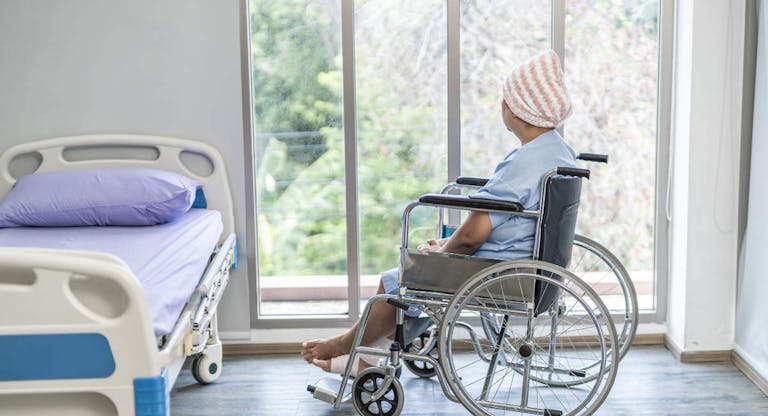 Senior female is cancer patients on wheelchair look at windows