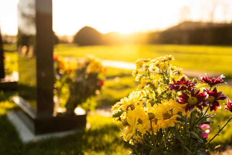 Dusk at a winter’s English cemetery seen with in-focus flowers in a burial plot.