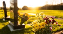 Dusk at a winter’s English cemetery seen with in-focus flowers in a burial plot.