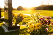 Dusk at a winter’s English cemetery seen with in-focus flowers in a burial plot.