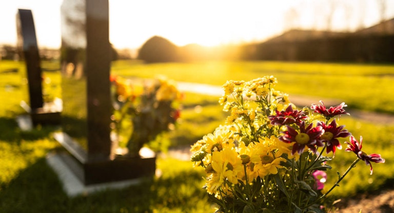 Dusk at a winter’s English cemetery seen with in-focus flowers in a burial plot.