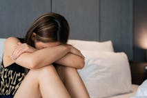 Depressed woman sitting on the bed at home
