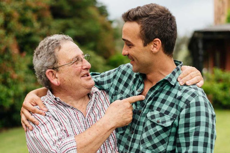 Father and adult son celebrating in their backyard