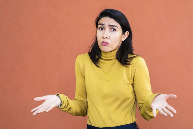 Latino woman shrugging with her hands to the sides