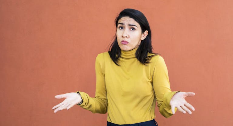 Latino woman shrugging with her hands to the sides