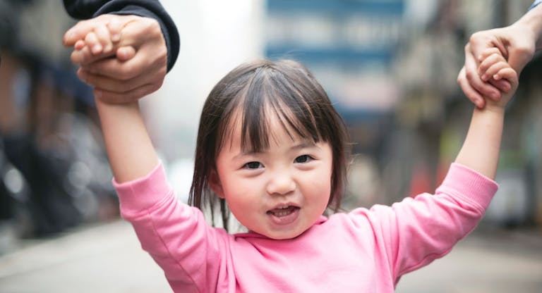 Cute little girl and parents walking on the street