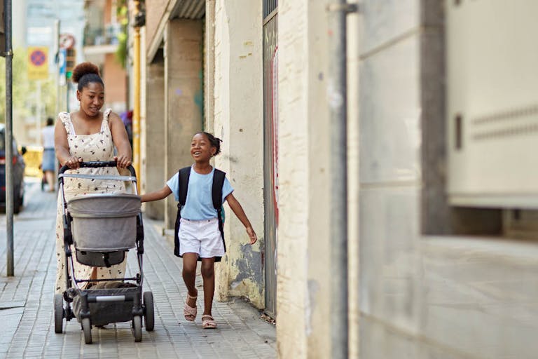 Black mother and young daughter talking on the way to school