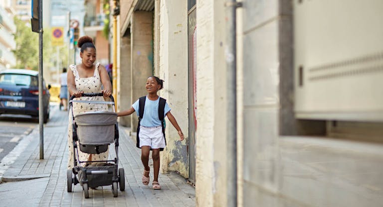 Black mother and young daughter talking on the way to school