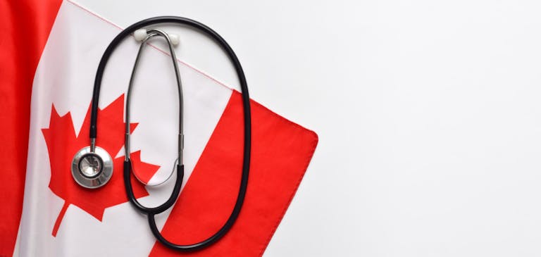 Canada healthcare concept, stethoscope on top of Canadian flag on white background with copy space