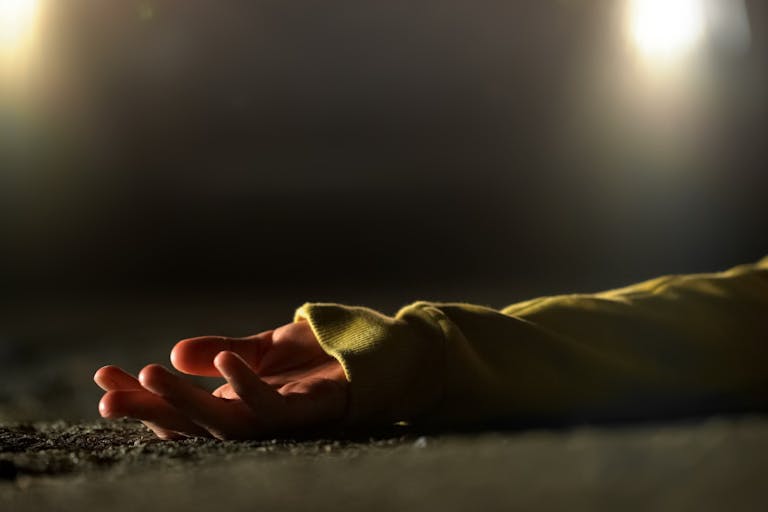 Bloody female victim of deadly car accident lying on road, close-up view at body