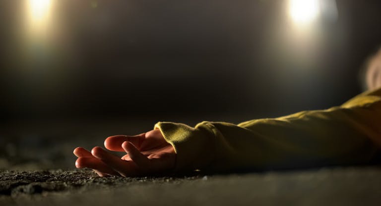 Bloody female victim of deadly car accident lying on road, close-up view at body