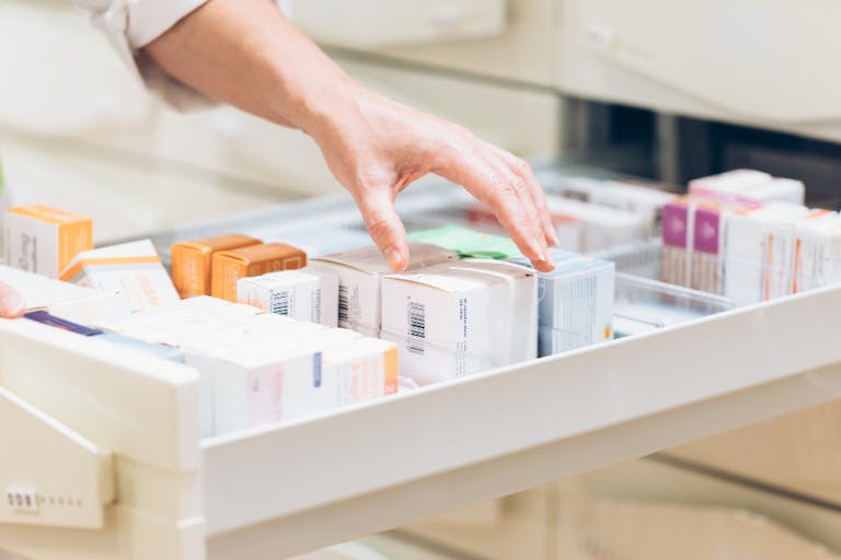 Pharmacist hand taking medication from drawer