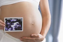 Pregnant Hispanic woman holding ultrasound printout