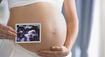 Pregnant Hispanic woman holding ultrasound printout