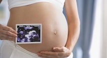 Pregnant Hispanic woman holding ultrasound printout