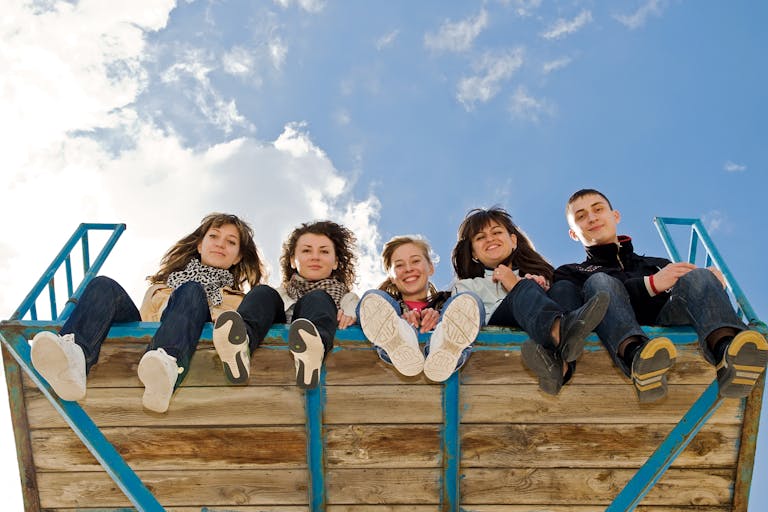 Company of five young people sitting together