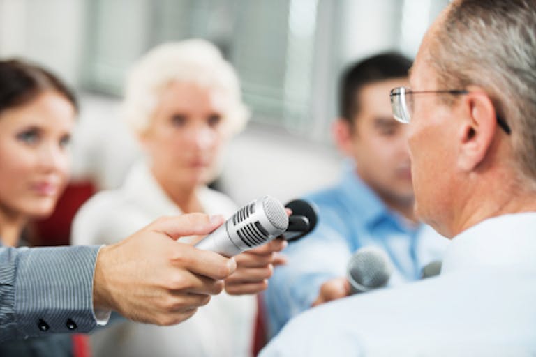 Male executive being questioned by journalists.media