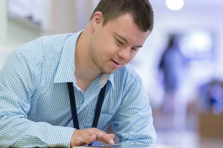 Caucasian man with Down Syndrome using digital tablet in hospital