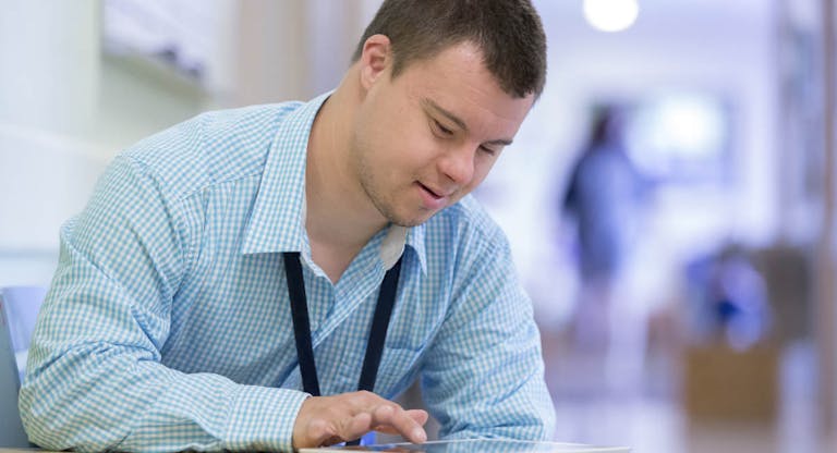 Caucasian man with Down Syndrome using digital tablet in hospital