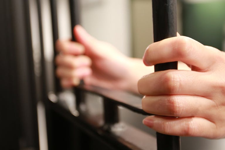 Female young Hand holding the window of jail
