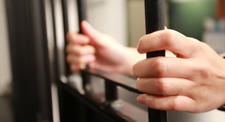 Female young Hand holding the window of jail