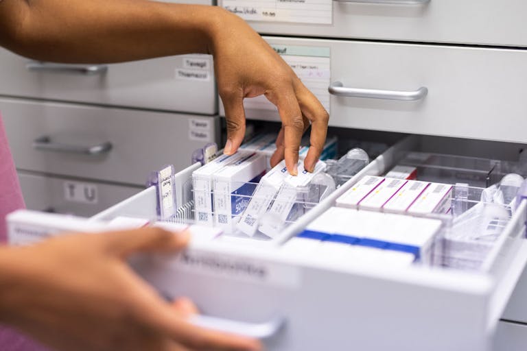 Close-up of a female pharmacist searching for prescription medicine in storage rack