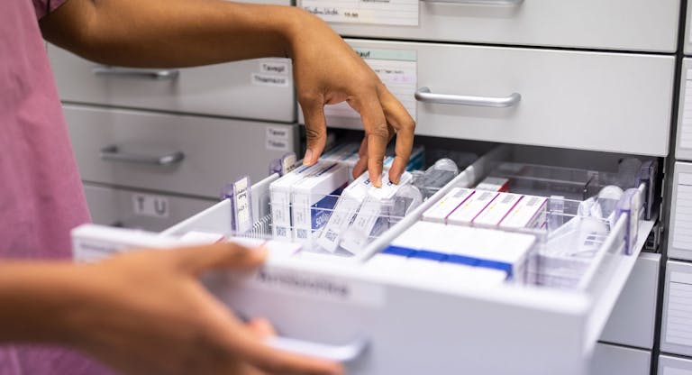 Close-up of a female pharmacist searching for prescription medicine in storage rack