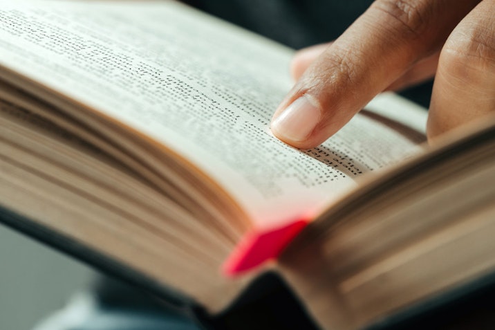 close-up of finger pointing text in Bible.close up of man reading through the Bible.