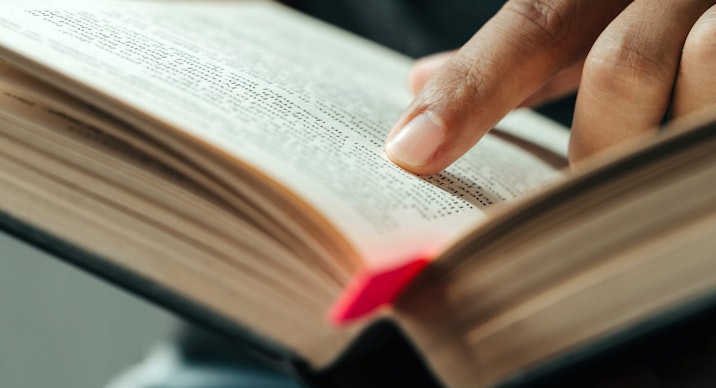 close-up of finger pointing text in Bible.close up of man reading through the Bible.