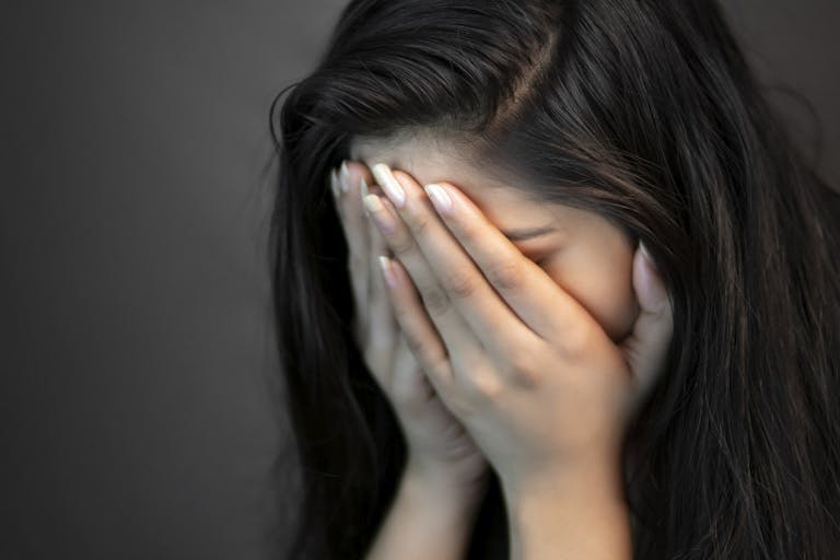 Photo: Getty Images Portrait of stress young woman covering her face with hands and crying.