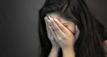 Portrait of stress young woman covering her face with hands and crying.