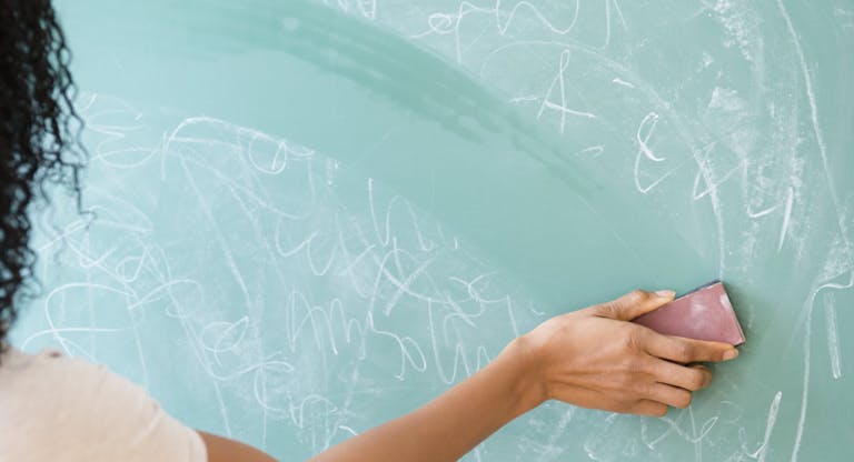USA, New Jersey, Jersey City, Rear view of woman erasing blackboard