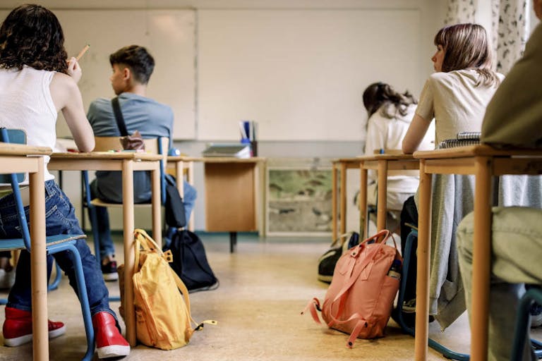 Multiracial group of students sitting at desk in classroom