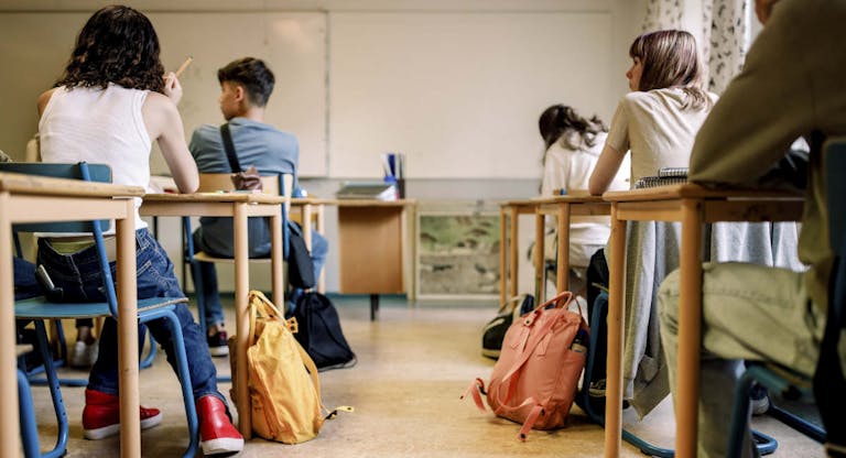 Multiracial group of students sitting at desk in classroom