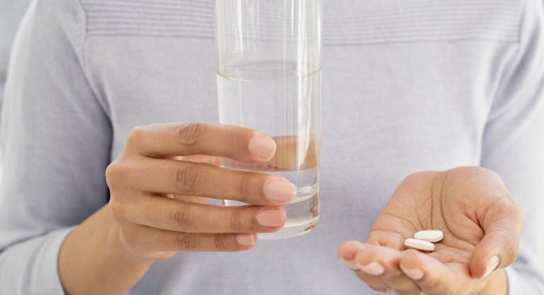 Woman holding tablets and water