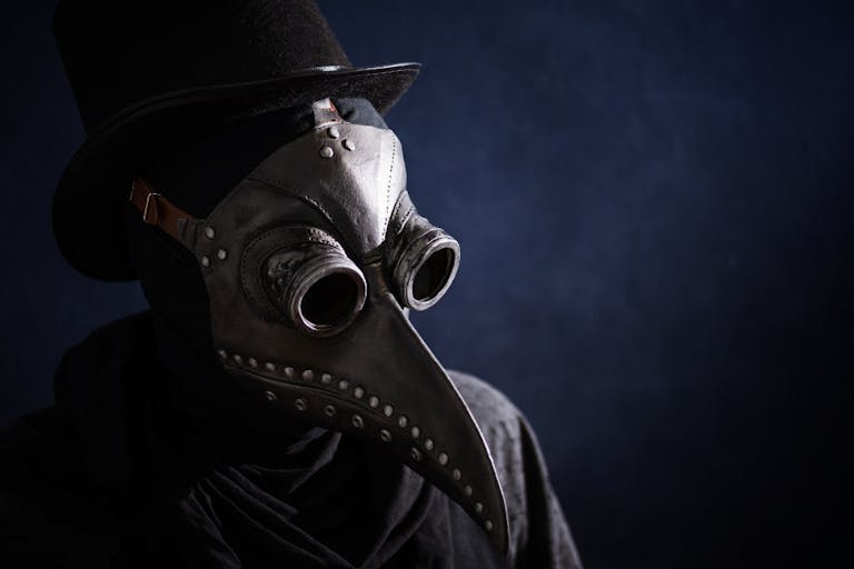 Masked man plague doctor, head profile, with bird mask and hat. Vintage style. Biohazard concept.