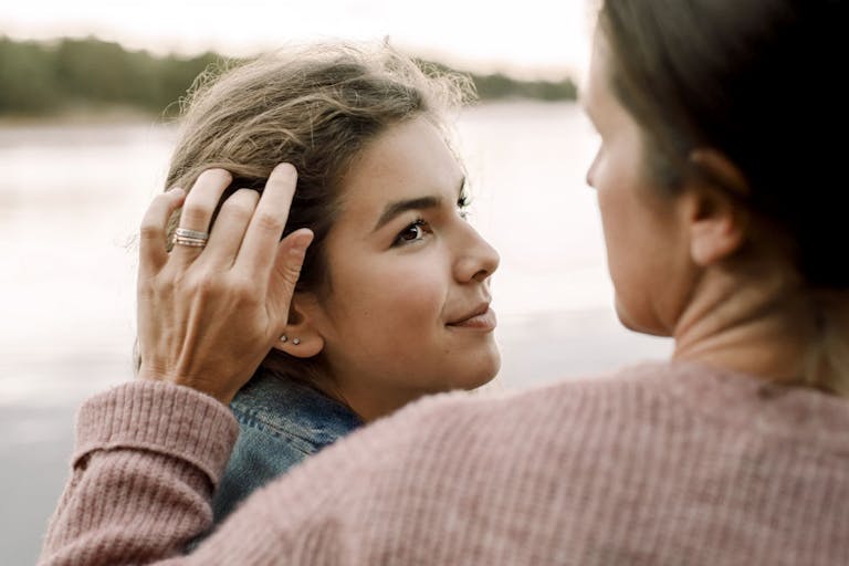 Smiling daughter looking at caring mother by lake