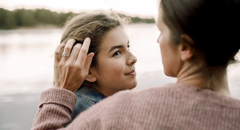 Smiling daughter looking at caring mother by lake