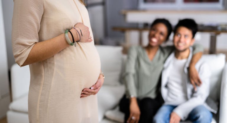 Pregnant Woman Touching Her Belly’s Woman Standing In Front