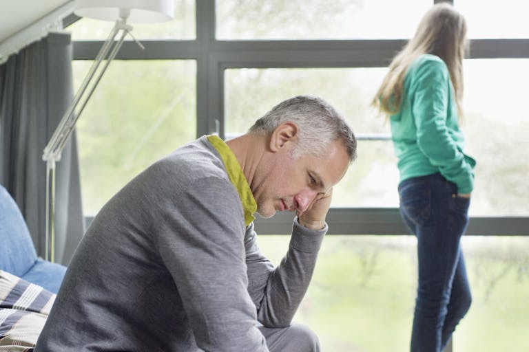 Man looking upset with his daughter standing in the background