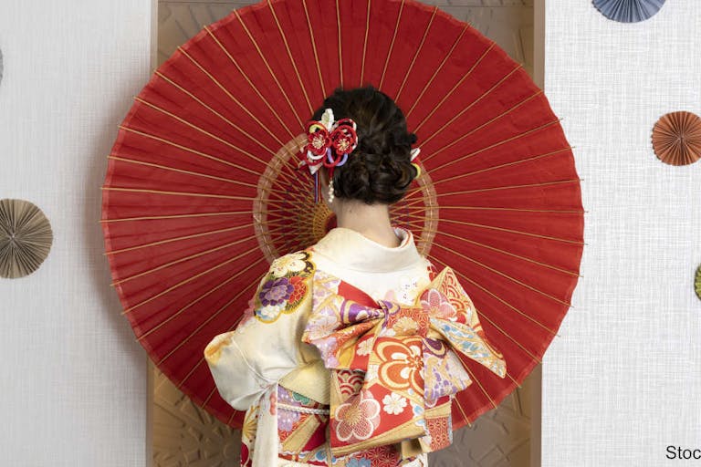 Female adult in kimono with an umbrella spread