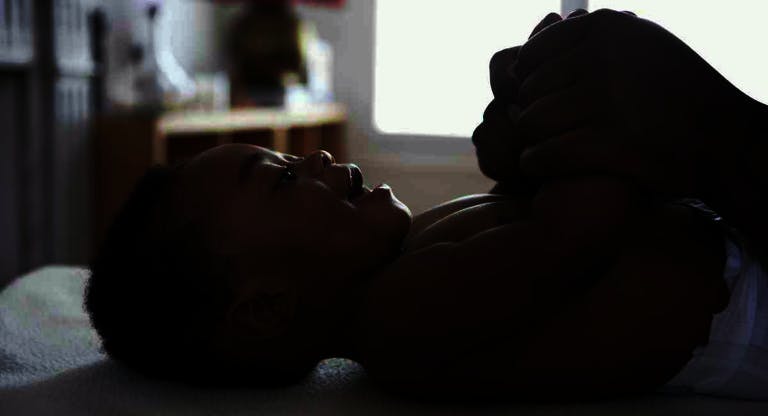baby lying down holding his mothers hands