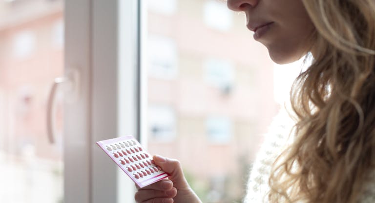 Young woman holding contraceptive pills