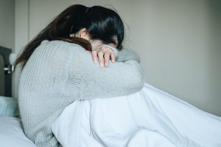 Image of woman crying with her head down. loss, abortion, Japan, miscarriage, abortion pill