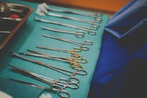 Photo: Shutterstock Dirty surgical tools laid out on a green table, abortionist