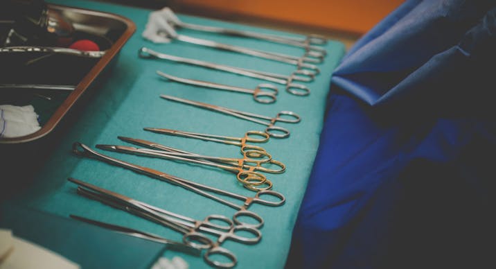 Dirty surgical tools laid out on a green table, abortionist